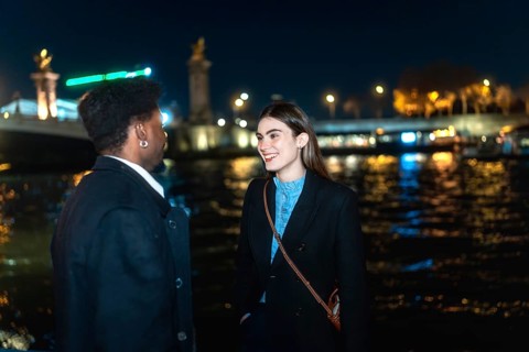 Young couple enjoying a romantic conversation by the illuminated river at night, sharing an