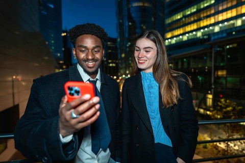 Diverse business colleagues smiling and looking at a smartphone together, enjoying a moment while