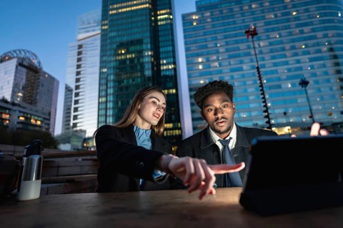 Diverse business colleagues working together on a digital tablet, pointing at the screen, with