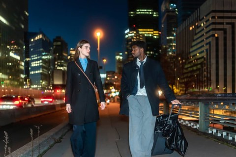 Business colleagues traveling together, walking on a city bridge with their luggage at night,