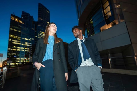Diverse business professionals sharing a cheerful moment, smiling and talking under the city lights