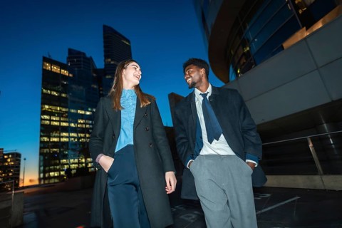 Diverse business colleagues walking down a city street at night, smiling and laughing together with