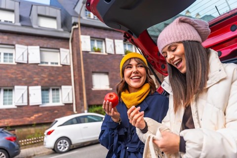 Two cheerful young multiracial women enjoying a moment of laughter while unloading fresh produce,