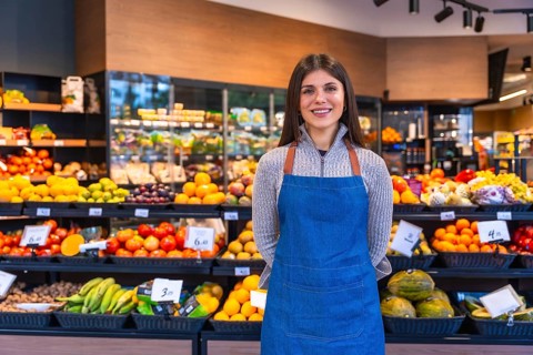 Greengrocer woman smiling and looking at the camera while standing proudly in a supermarket,