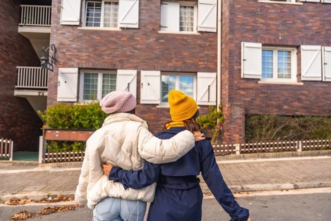Two friends walking arm in arm down a european city street, enjoying an autumn day together in warm