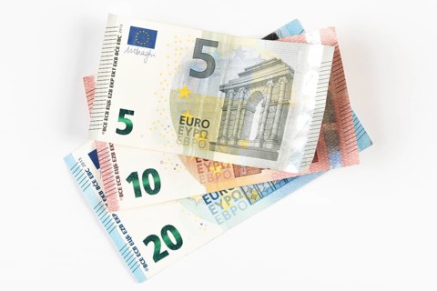 Stacked euro banknotes in denominations of 5, 10 and 20 on a white background
