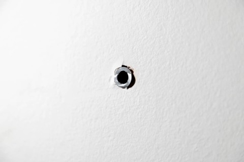 Single drill hole with dowel in a white wall
