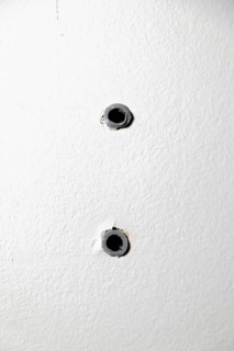 Two drill holes with dowels in a white wall
