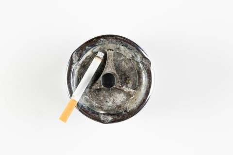Used ashtray with cigarette, on white background
