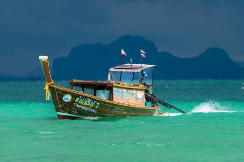 Longtail boat in fast drive to the beach, behind it an approaching thunderstorm, Koh Ngai island,