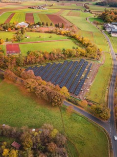 View of solar panels in rural area with roads and autumn trees, PV Freifaechenanlage construction,