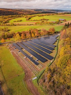 Aerial view of a large solar plant in an autumn landscape with fields and trees, PV