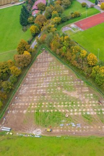 Parceled green area in triangle shape, surrounded by trees and infrastructural facilities, PV