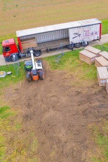 A forklift unloads boxes from a truck in a field next to a road, Bau PV Freifaechenanlage, Weil der