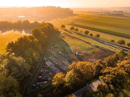 Morning landscape with warm lighting and trees next to construction, PV Freifaechenanlage