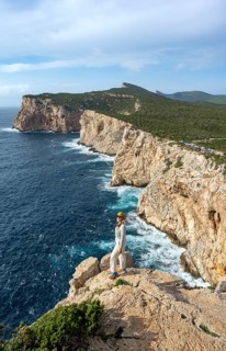 Tourist enjoying the view of steep cliffs by the sea, coastal landscape, cliffs on the Capo Caccia