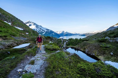 Hikers on Portage Pass, snow-covered mountains and Fjord Passage Canal, near Whittier, Alaska, USA