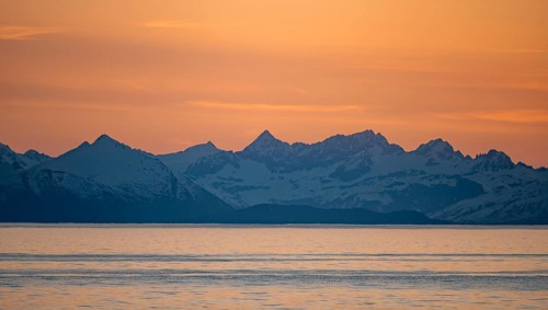 View of Cook Inlet on white mountain peaks of the Aleutian Range, picturesque golden light of the