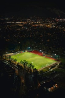 Illuminated soccer field in an urban area at night with glowing city lights, Sindelfingen,