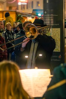 Musician plays trombone at an evening concert in a festive setting, Christmas market 2025, Nagold,