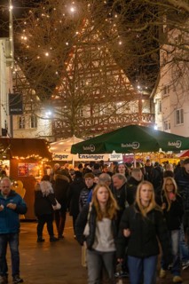 People stroll through a well-visited, festively lit Christmas market, Christmas market 2025,
