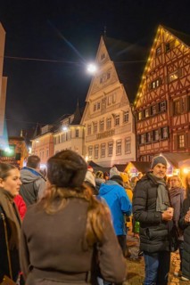 People enjoy a Christmas market evening surrounded by half-timbered houses and atmospheric lights,