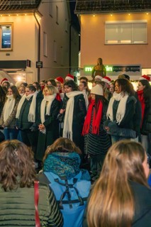 Choir sings in the evening in a Christmas atmosphere, surrounded by spectators, Christmas market