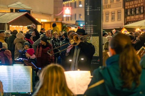 Street musicians play outdoors on a busy shopping street at night, Christmas market 2025, Nagold,