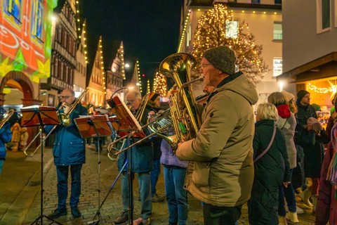 A brass band plays at night in front of Christmass-illuminated buildings, Christmas market 2025,
