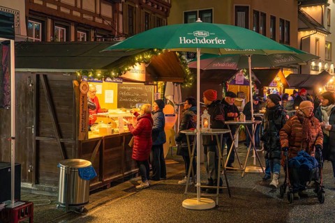 Residents and visitors gather around a food stand with festive lights, Christmas market 2025,