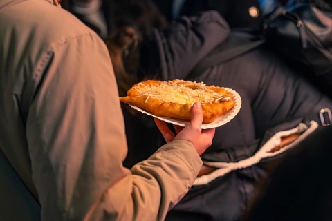 A person holds a plate of hot flatbread at a Christmas market, Christmas market 2025, Nagold, Black