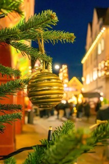Golden Christmas ball on a pine branch in a festively lit area, Christmas market 2025, Nagold,