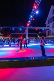 Colourful lights on an ice rink at night, people skating and friendly togetherness, Christmas