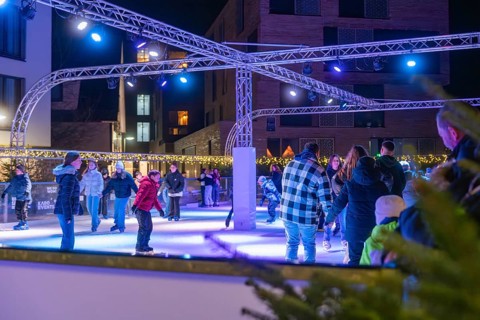 People skating on an illuminated area surrounded by a winter atmosphere, Christmas market 2025,