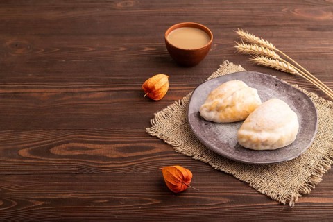 Glazed Pies with Cowberry jam on brown wooden background and linen textile, cup of coffee, side