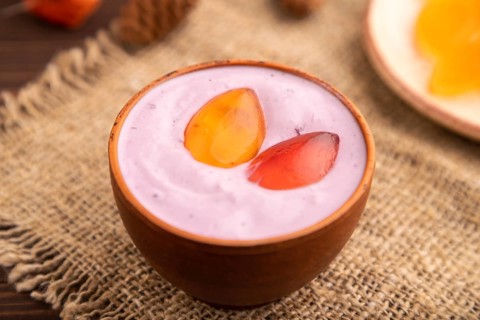 Purple Yogurt, with jelly candy on brown wooden background and linen textile, side view, close up,