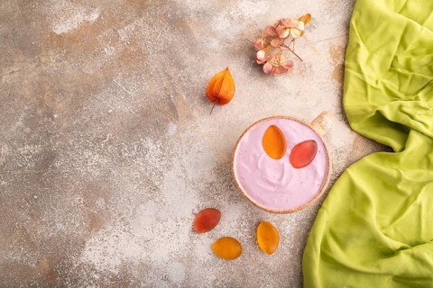 Purple Yogurt, with jelly candy on brown concrete background and green textile, top view, flat lay,