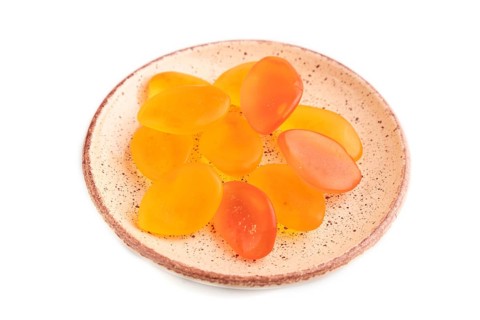 Jelly candies on ceramic plate isolated on white background, side view, close up