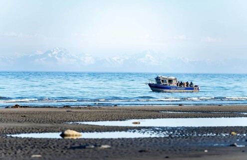 View over Cook Inlet to white mountain peaks of the Aleutian Range, motor boat on the ocean, Anchor