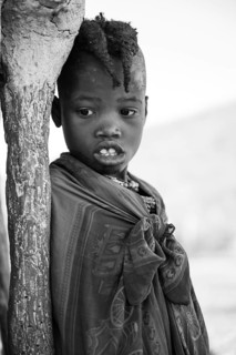 Black and white, Himba girl leaning at a traditional clay hut, in the morning, traditional Himba