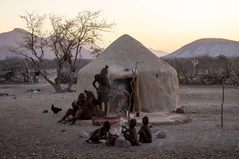Himba woman and children sitting in front of a hut, sunrise, traditional Himba village, Kaokoveld,