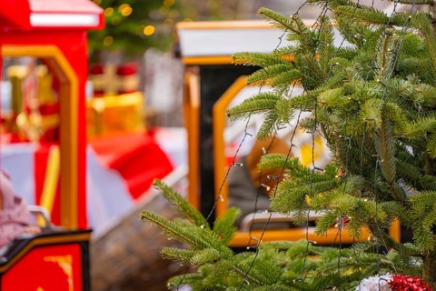 A decorated Christmas tree with lights next to a brightly decorated toy train, Sindelfingen,