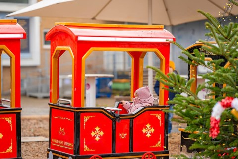 A child sits on a red miniature train next to a Christmas tree at a market, Sindelfingen, Böblingen