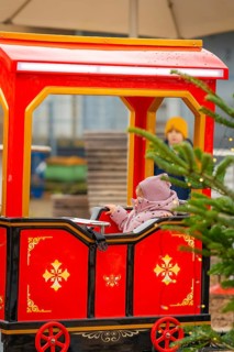 Little girl sitting on a red toy train at a Christmas market, Sindelfingen, Böblingen district,