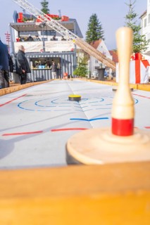 A wooden bowling game at a Christmas market with spectators standing in the background,