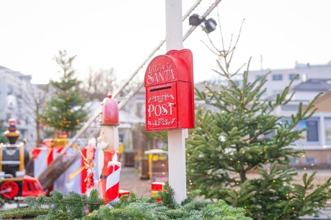 Red Christmas mailbox in front of Christmas tree and lights at a festive market, Sindelfingen,