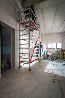 High scaffolding in an unfinished interior with a worker, construction in progress, electrician,