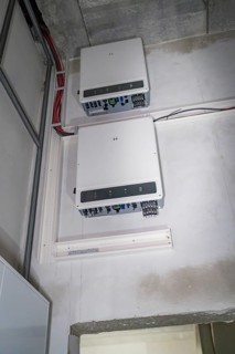 Two electronic devices are mounted on a wall, with visible cables and connections, electrician,