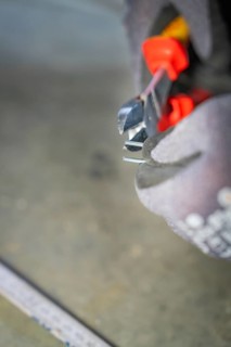 Close-up of pliers cutting wire while a glove-clad hand holds them, electrician, Neubau, Germany