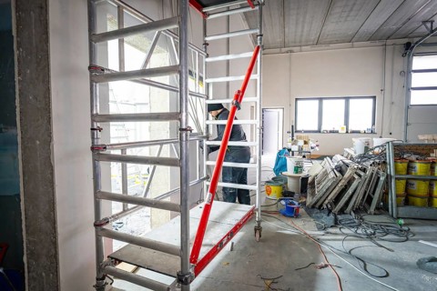 Interior on construction site with scaffolding, cables and building materials, lighting through